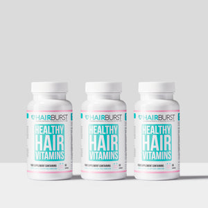 Three bottles of Hairburst Healthy Hair Vitamins on a light gray background